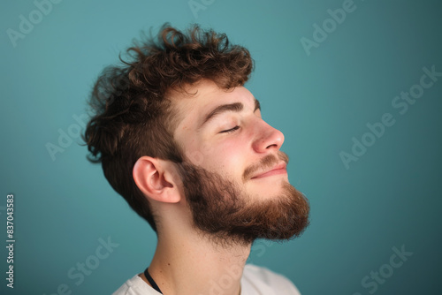 A close up of a man with beard and closed eyes looking to a side