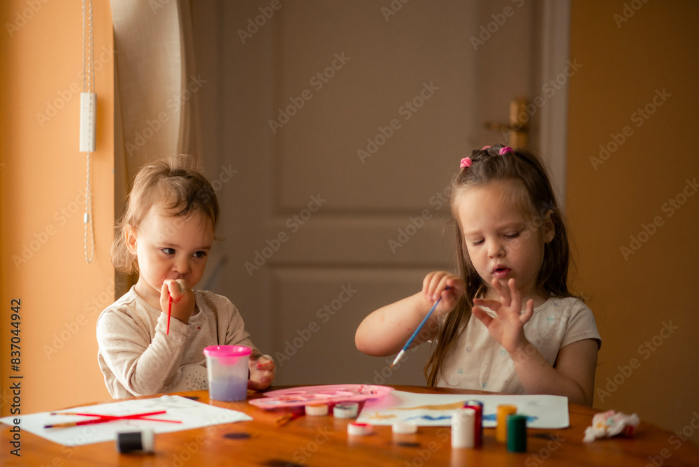 two sisters paint with paints, one is 1 year old and the older one is 5 years old. two sisters paint with paints, one is 1 year old and the older one is 5 years old.