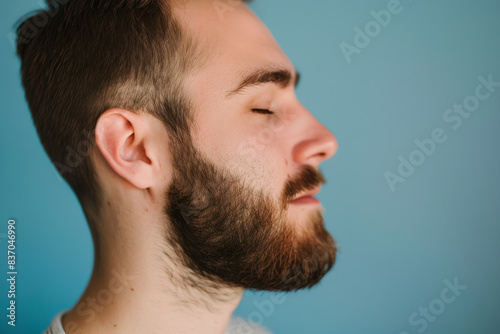 A close up of a man with beard and closed eyes looking to a side