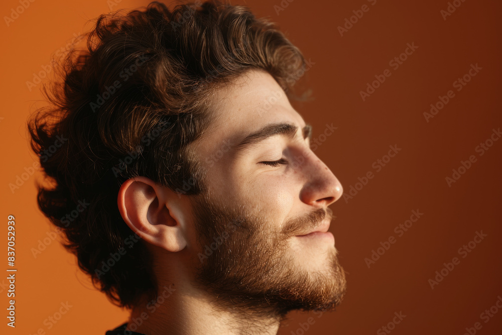 A close up of a man with beard and closed eyes looking to a side