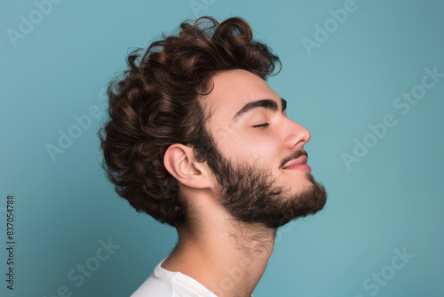 A close up of a man with beard and closed eyes looking to a side