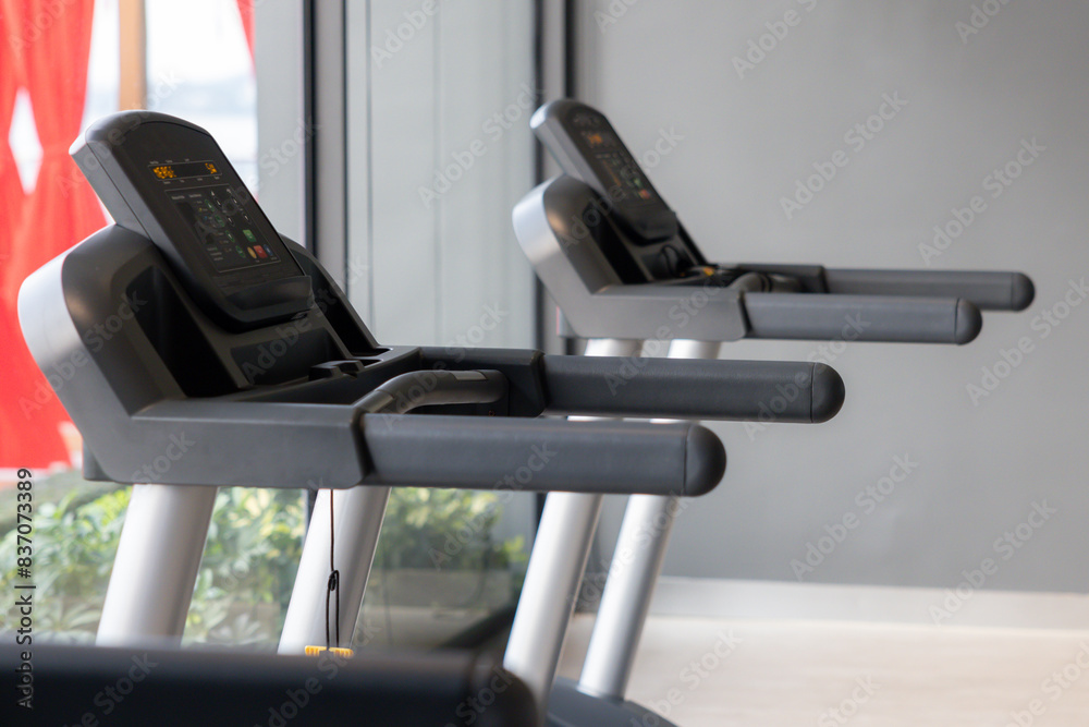 Two treadmills are in a gym, one of which is empty Two treadmills are in a gym, one of which is empty