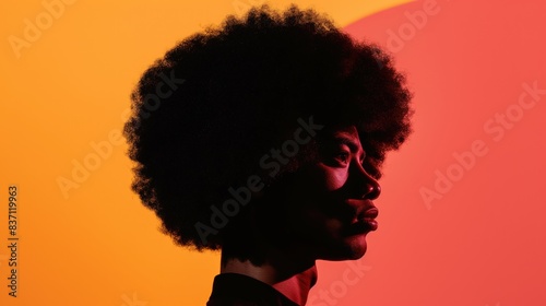 A side profile of a Black man with an afro against a bright red and orange background