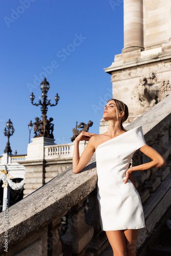 Beautiful fashionable vogue model with an elegant white dress in the city. Travel to Paris. Ideas for a photo session.