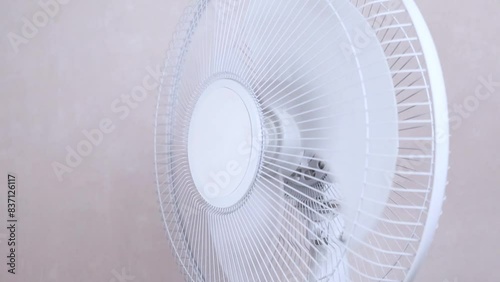 Electric Floor fan turned on white on beige background. Relief Help from the heat, hot summer. Slowmotion video, copy space, close up photo