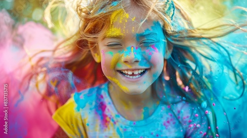 Close-up of a happy child with bright paint splattered on her face.