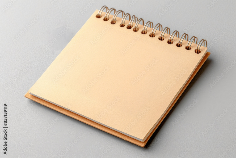 A spiral bound notebook with a blank page sits on a gray surface. The notebook is a simple, unadorned design with a plain cover and no writing on the page. Concept of emptiness and potential A spiral bound notebook with a blank page sits on a gray surface. The notebook is a simple, unadorned design with a plain cover and no writing on the page. Concept of emptiness and potential