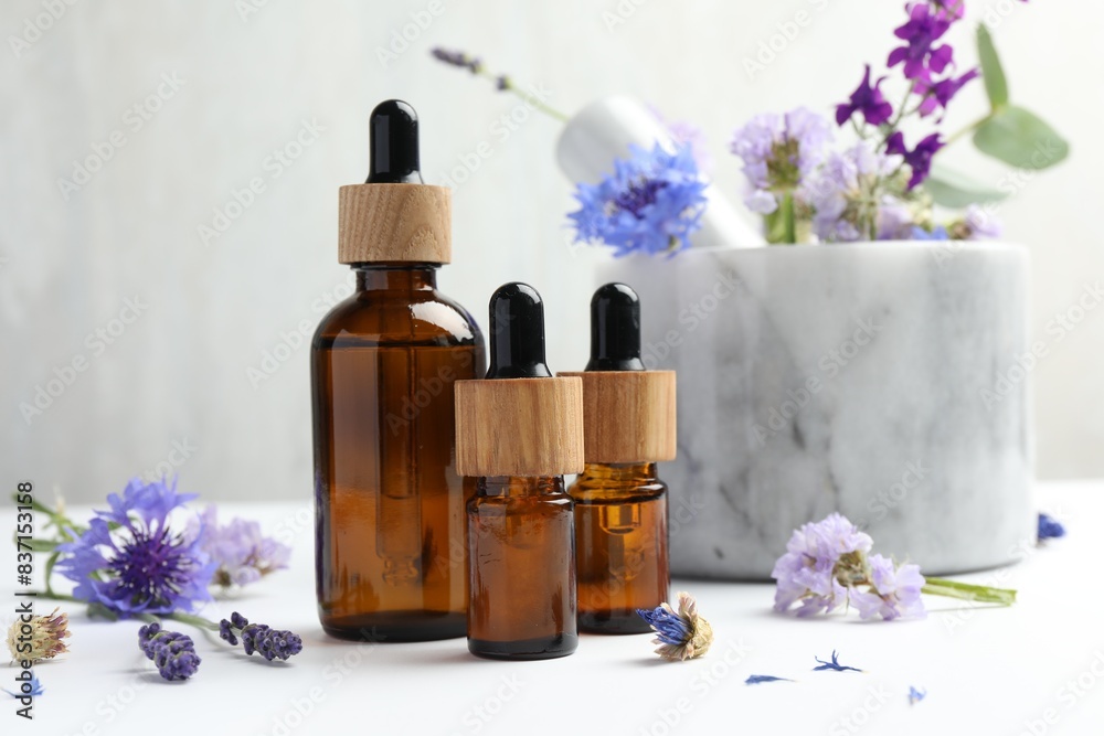 Aromatherapy. Essential oils, flowers, mortar and pestle on white table Aromatherapy. Essential oils, flowers, mortar and pestle on white table