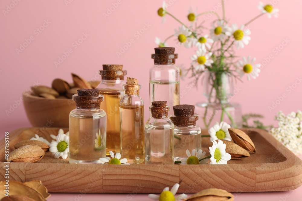 Aromatherapy. Different essential oils, flowers and almonds on pink background Aromatherapy. Different essential oils, flowers and almonds on pink background