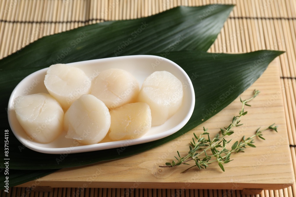 Fresh raw scallops, thyme and green leaves on bamboo mat Fresh raw scallops, thyme and green leaves on bamboo mat