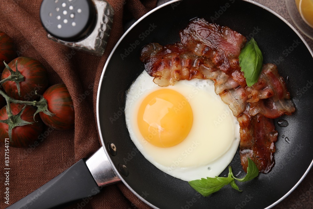 Fried egg, bacon, basil and tomatoes on table, top view Fried egg, bacon, basil and tomatoes on table, top view