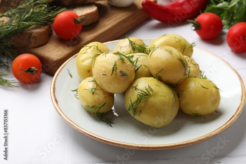 Tasty young boiled potatoes with dill and other products on white table
