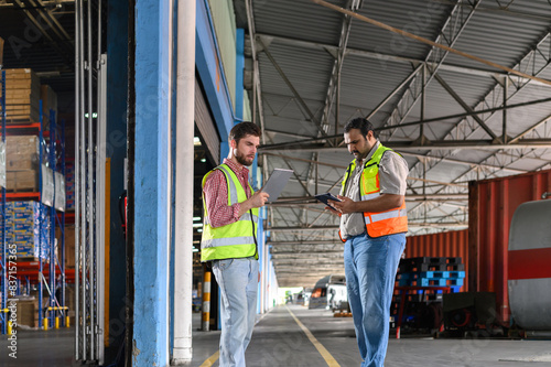 Two Warehouse worker in safety uniform check the stock order details and goods supplies in the workplace warehouse. industry logistic export import distribution concept.
