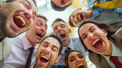 Group of coworkers shares a hearty laugh while gathered in a well-lit office space. Their expressions show joy and camaraderie  highlighting a moment of fun at work