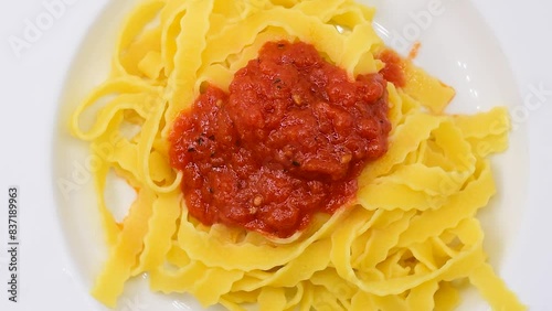 Plate of curly egg Fettuccine rough pastry with rustic tomato sauce.Piatto di Fettuccine Ricce all'uovo sfoglia ruvida con sugo di pomodoro rustico.Close-up,rotating video photo