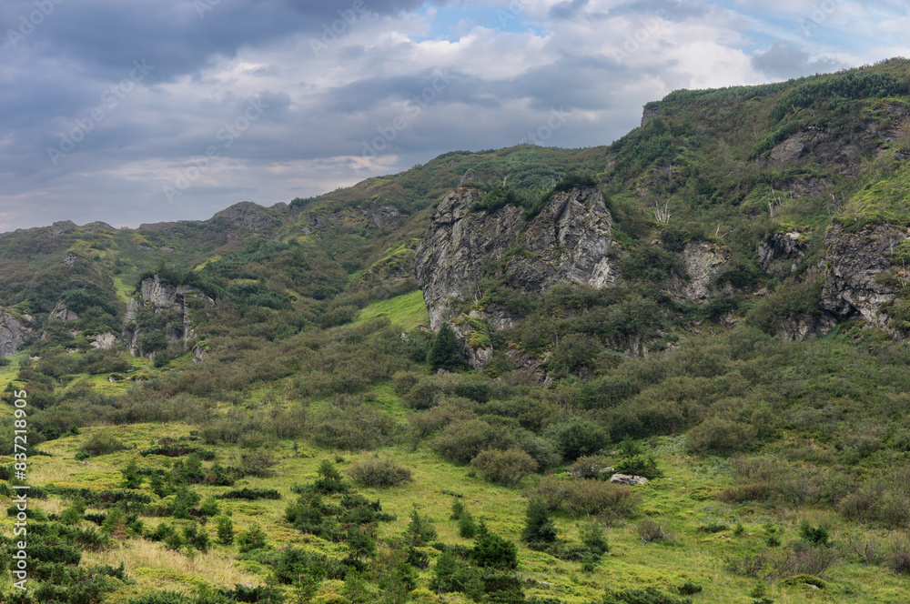Fototapeta premium Steep mountain slope with rocky ledges. Mountain range on the border of Ukraine and Romania on a cloudy, summer day