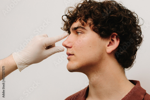 Rhinoplasty to change size or shape of nose and fix issues from injury or improve breathing problems. ENT doctor touching nose of patient before rhinoplasty or septoplasty surgery. photo