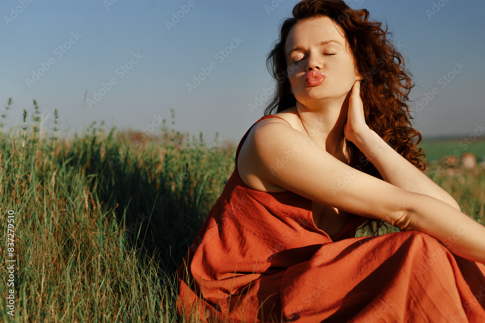 Obraz premium Beautiful long-haired young brunette woman in red long dress outdoors, woman in dress in nature