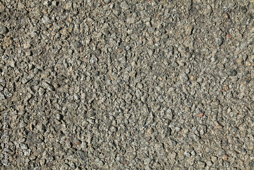 Grey road backdrop. Asphalt surface, covered with stones on the resin base. Detailed texture and background of the road close-up. Uneven, rocky surface. Road foundation. Highway and freeway coating