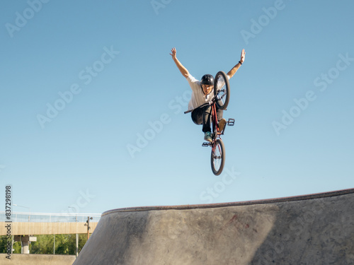 BMX bicycle rider doing trick No Hand in quarter
