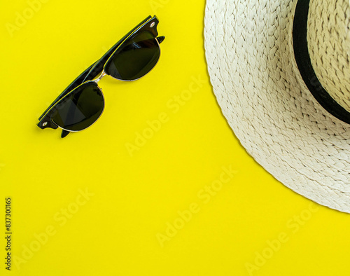 Flatlay, summer vacation. Straw hat and sunglasses on a yellow background.