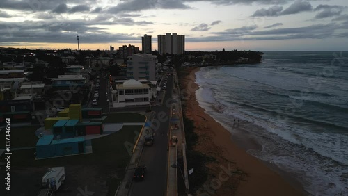 aerial view of luquillo puerto rico skyline with waves crashing on the beach (tropical caribbean island town at sunset, dusk) night time tall hotel apartment buildings sand sea ocean paradise photo