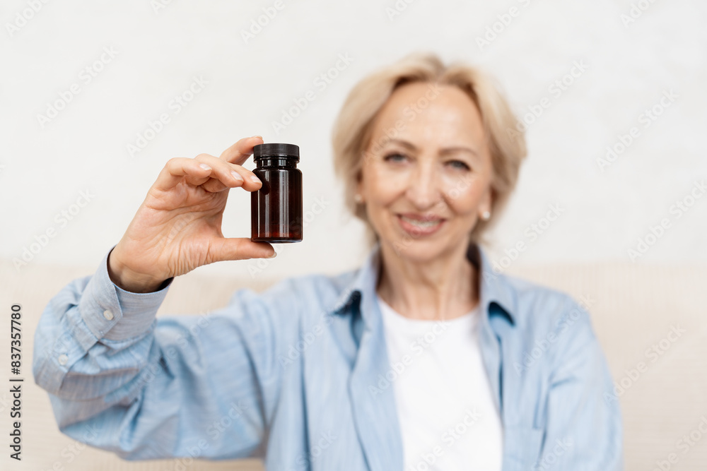 Smiling Elderly Woman Holding Medicine Bottle in Her Hand, Wearing in Blue Shirt Smiling Elderly Woman Holding Medicine Bottle in Her Hand, Wearing in Blue Shirt