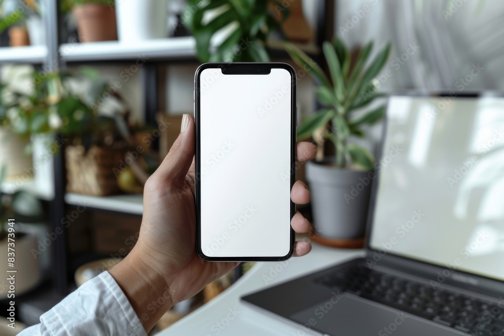 Person holding phone in front of laptop