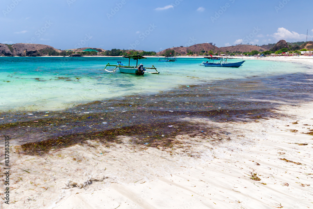 Obraz premium Plastic and other trash floating in a tropical ocean next to a beach