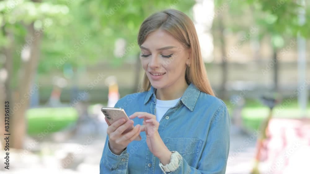 Woman Text Messaging on Phone Outdoor in Park Woman Text Messaging on Phone Outdoor in Park