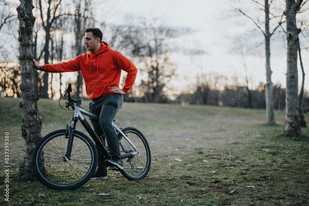 A relaxed young man with his bike takes in the serenity of an urban park at dusk, reflecting a commitment to fitness and well being. A relaxed young man with his bike takes in the serenity of an urban park at dusk, reflecting a commitment to fitness and well being.