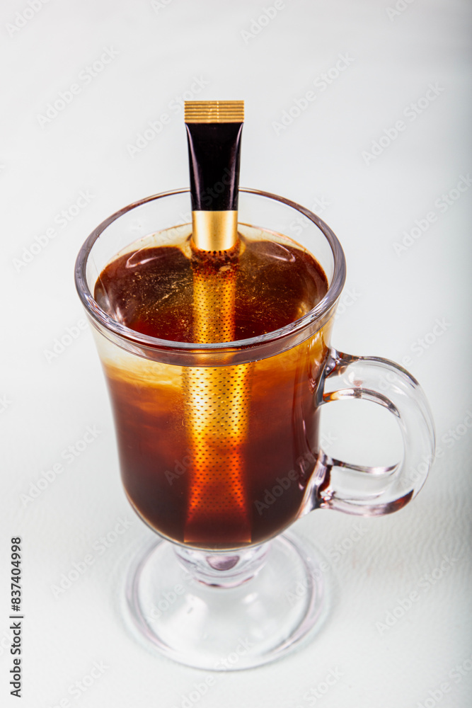 A glass cup of freshly brewed drip coffee. Female hands hold a bag of brewed drip coffee in a glass cup. Drip Pour over Brew Coffee. A glass cup of freshly brewed drip coffee. Female hands hold a bag of brewed drip coffee in a glass cup. Drip Pour over Brew Coffee.