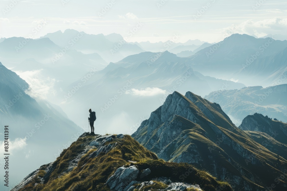 A serene mountain landscape with a lone hiker standing on a peak, looking out over the horizon.