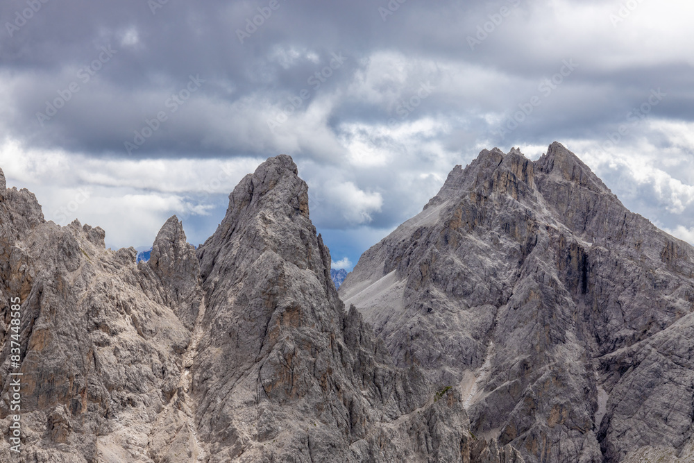 Dolomiti Alps beautiful mountain landscape. Rocky tower alpine summits in the Dolomites. Summer mountain scenic view on the hiking trekking path in the green mountain valley and blue sky with clouds Dolomiti Alps beautiful mountain landscape. Rocky tower alpine summits in the Dolomites. Summer mountain scenic view on the hiking trekking path in the green mountain valley and blue sky with clouds