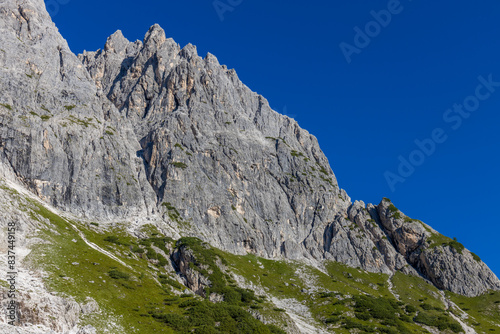 Dolomiti Alps beautiful mountain landscape. Rocky tower alpine summits in the Dolomites. Summer mountain scenic view on the hiking trekking path in the green mountain valley and blue sky with clouds