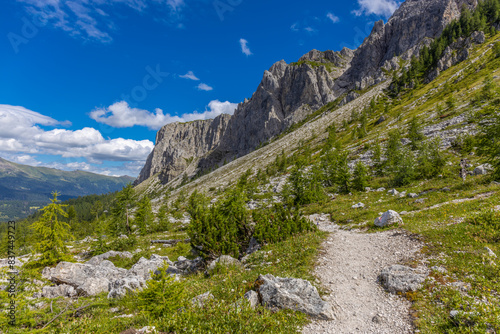 Dolomiti Alps beautiful mountain landscape. Rocky tower alpine summits in the Dolomites. Summer mountain scenic view on the hiking trekking path in the green mountain valley and blue sky with clouds