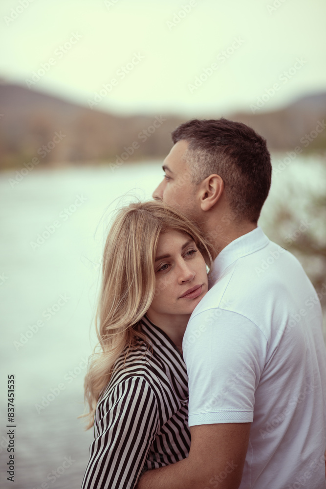 Naklejka premium Couple standing by the river, man hugging woman.