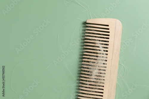 Wooden comb with lost hair on green background  top view. Space for text