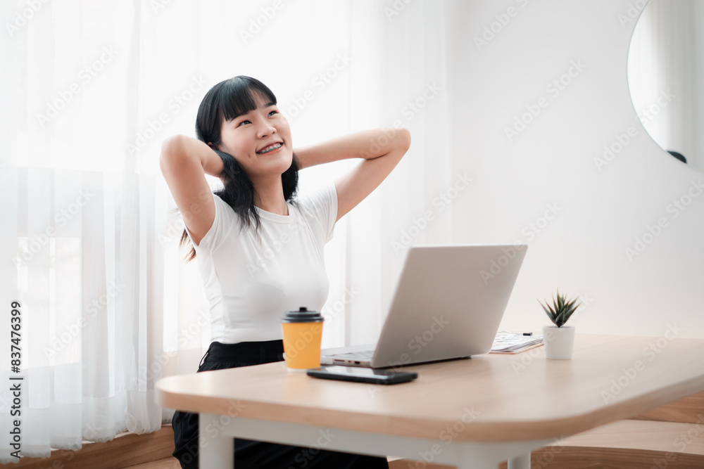 Young Woman Relaxing at Desk with Laptop and Coffee in Bright Modern Home Office Young Woman Relaxing at Desk with Laptop and Coffee in Bright Modern Home Office