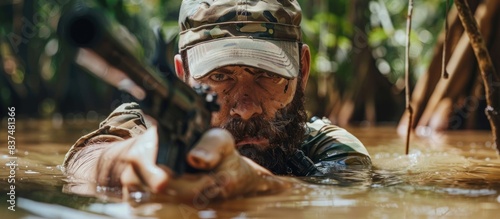 A man in camouflage gear is in the water with a gun photo