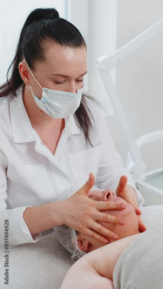 Therapist doctor making woman relaxing spa face chin massage with hands. Smooth, healthy skincare treatment at salon. Detox and healing. Client in facial physical cosmetology session. Vertical shot
