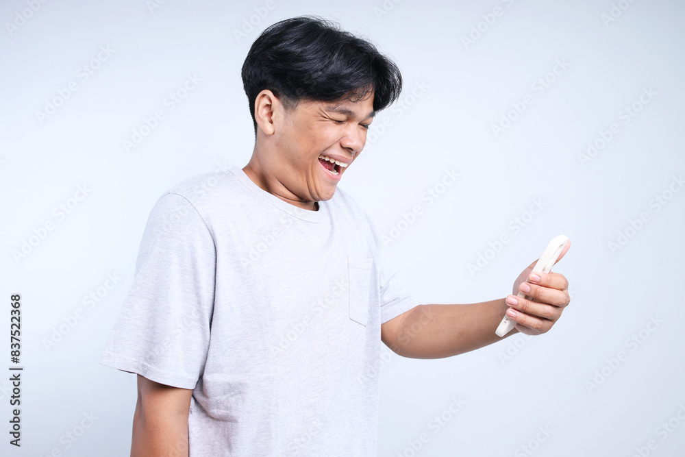 Potrait Of Funny Young Asian Man Laughing At Smartphone Potrait Of Funny Young Asian Man Laughing At Smartphone