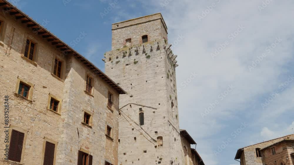 Sunny day in San Gimignano over historic Tuscan stone buildings with clear blue sky. Sunny day in San Gimignano over historic Tuscan stone buildings with clear blue sky.