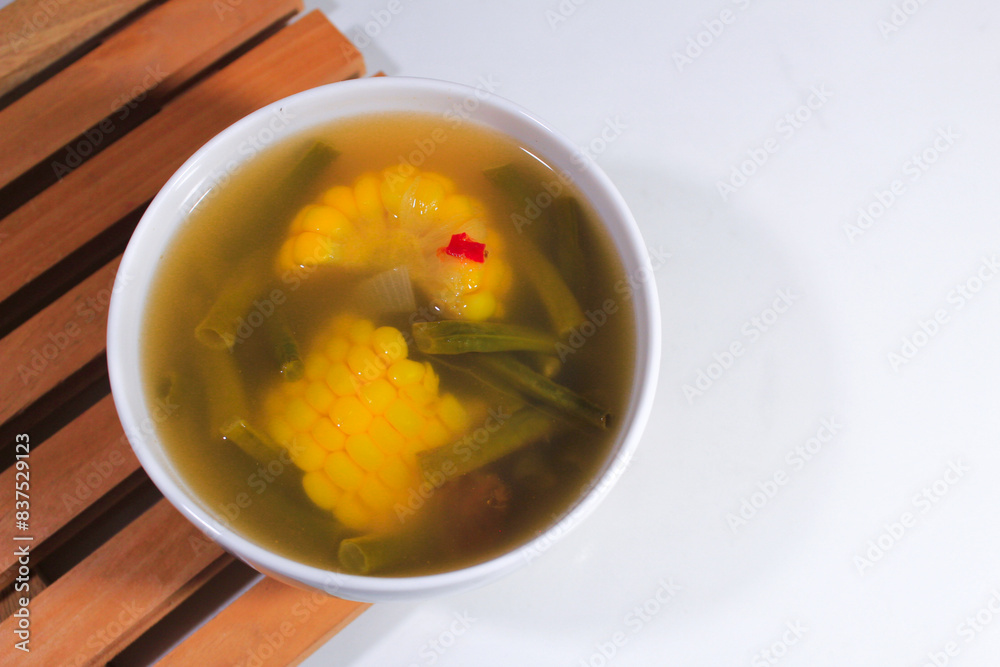 sweet and sour corn vegetable soup with porcelain bowl and wooden coaster sweet and sour corn vegetable soup with porcelain bowl and wooden coaster