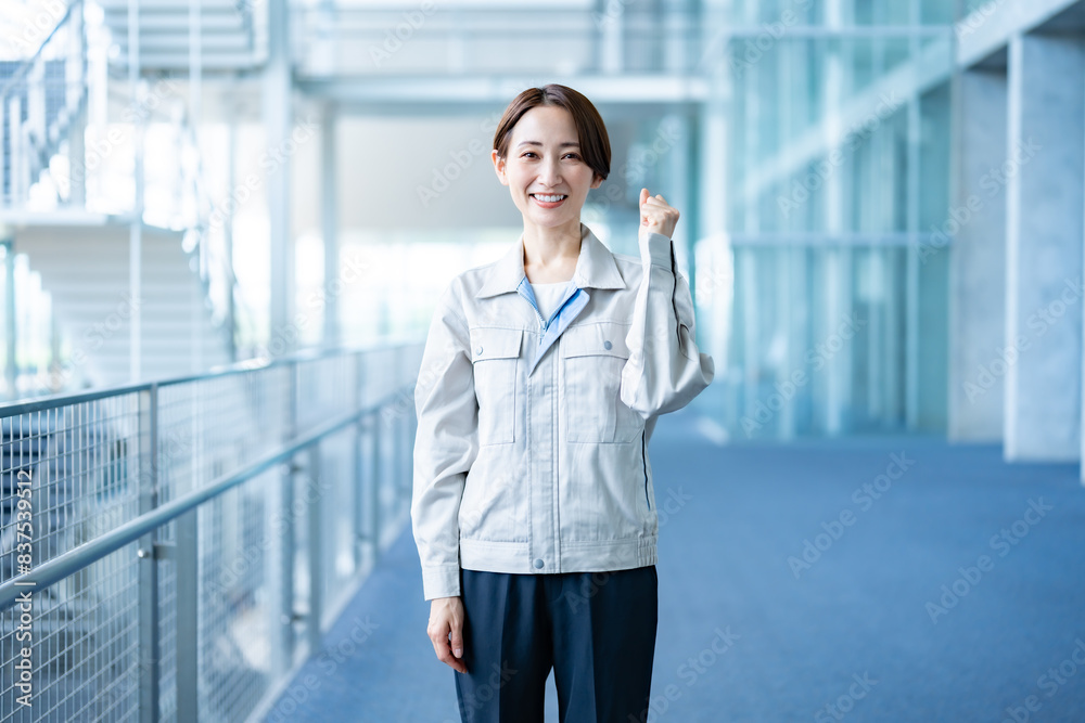 室内でガッツポーズをする作業着を着たショートヘアーの女性 室内でガッツポーズをする作業着を着たショートヘアーの女性