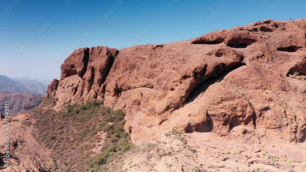 Aerial Drone tracking across dry red rocky ridge towards mountain valley in Gran Canaria Spain Aerial Drone tracking across dry red rocky ridge towards mountain valley in Gran Canaria Spain