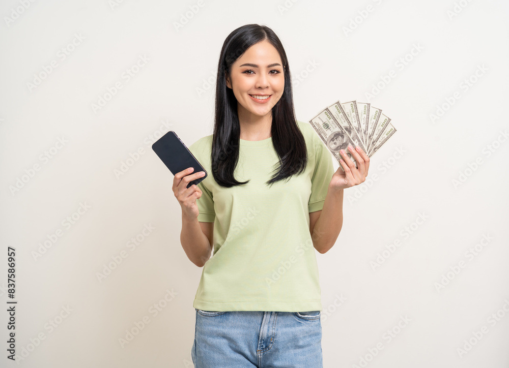 Cheerful young Asian business woman showing lot of money and smartphone. Attractive female with dollar banknotes. Happy asian woman counting money us dollar on isolated white background Cheerful young Asian business woman showing lot of money and smartphone. Attractive female with dollar banknotes. Happy asian woman counting money us dollar on isolated white background