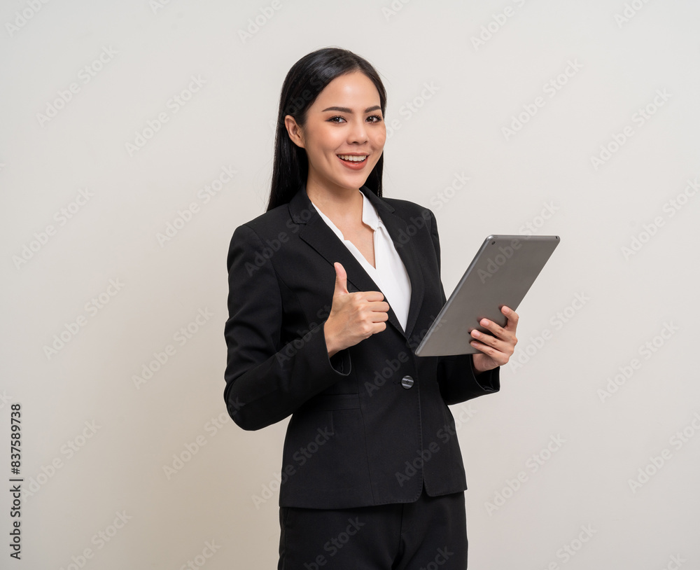 Attractive elegant young asian business woman using digital tablet standing on isolated background. Happy young latin female formal black suit holding tablet gadget working service with customer Attractive elegant young asian business woman using digital tablet standing on isolated background. Happy young latin female formal black suit holding tablet gadget working service with customer