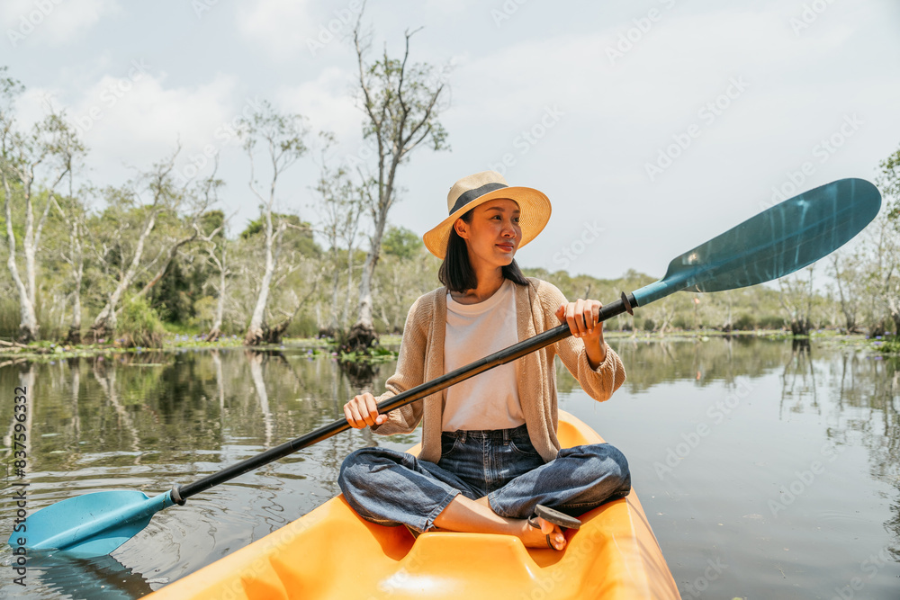 Holiday travel activities. Happy asian woman rowing a canoe or kayak in mangrove forests. Young traveler with kayak at botanical garden tropical mangrove forest in a national park. Holiday travel activities. Happy asian woman rowing a canoe or kayak in mangrove forests. Young traveler with kayak at botanical garden tropical mangrove forest in a national park.