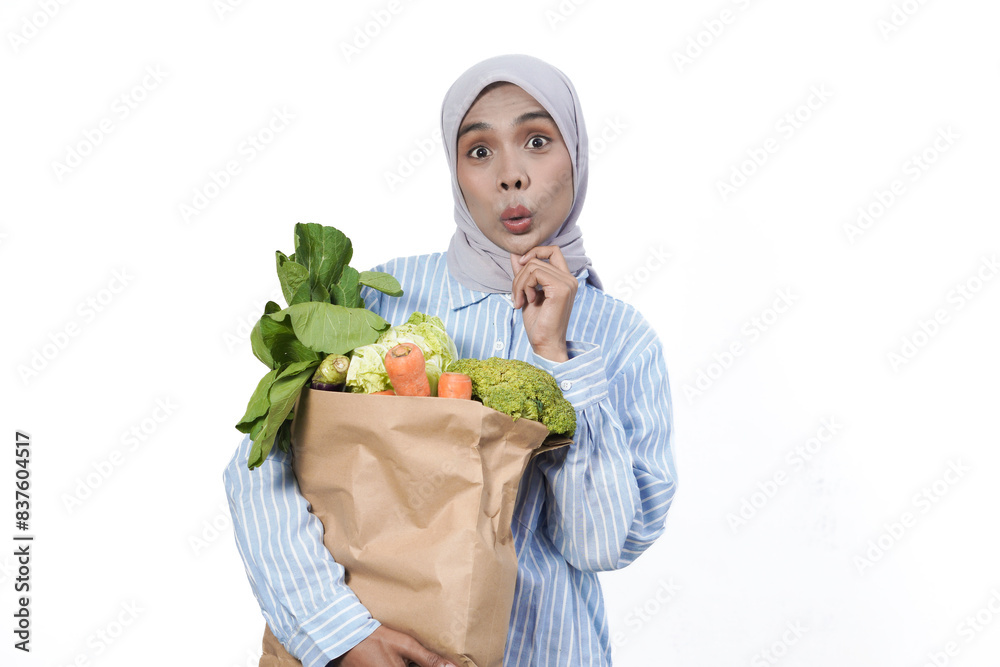 Young woman wear casual clothes hold brown paper bag with vegetable products isolated on white background studio portrait Young woman wear casual clothes hold brown paper bag with vegetable products isolated on white background studio portrait